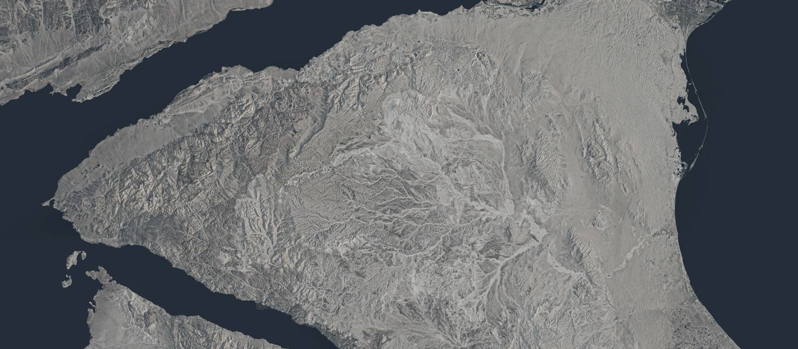 Satellite view of arid terrain meeting a dark coastline