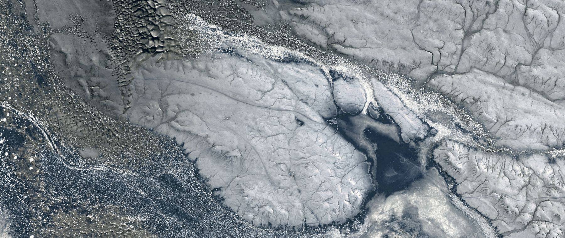 Satellite view of braided river channels crossing snow-covered terrain